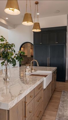 a large kitchen with marble counter tops and gold pendant lights hanging from the ceiling over the sink