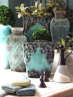 three vases with plants in them sitting on a table next to each other,