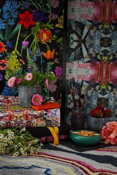 a table with flowers on it in front of a wallpapered background and vases