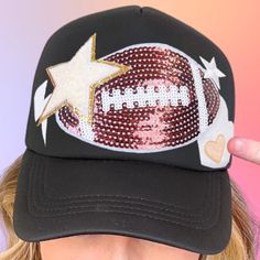 Football Patch Trucker Hat  A mesh back trucker style hat with a plastic snap closure. This trucker hat's design features a sequin patch of a Football in the center, along with several other overlapping patches of stars, hearts, lightning bolts, smooching lips, and smileys, in a variety of types, such as embroidery, chenille, vinyl, and velvety flock. This accessory is perfect for Football game day! Note: Some components may vary somewhat depending on availability.  Sizing Hint: This is a standa Team Mom Gifts Football, Football Kicker, Team Mom Gifts, Football Diy, Mom Hat, Custom Trucker Hats, Lightning Bolts, Sequin Patch, Mom Hats