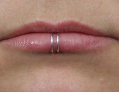 a woman's lip with two silver rings on it