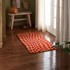 a red and yellow area rug sitting on top of a wooden floor next to a window