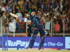 a cricket player hitting the ball with his bat in front of an audience at a stadium