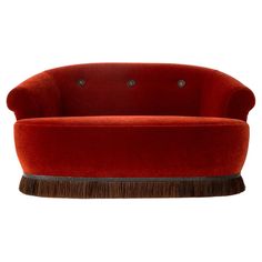 a red velvet couch with wooden legs and round back rests against a white background,