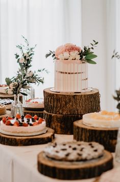 a table topped with cakes and desserts on top of wooden slices covered in frosting