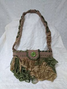 a crocheted purse sitting on top of a white cloth covered tablecloth with a green button in the center