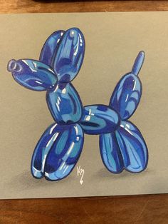 a blue balloon dog sitting on top of a piece of paper next to a pen