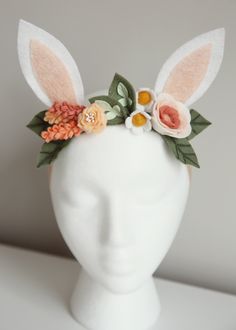 a white mannequin head with flowers and bunny ears