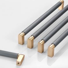 four different types of metal rods on a white surface with gold colored handles and ends