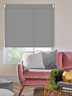 a living room with pink couches and grey shades on the window sill,