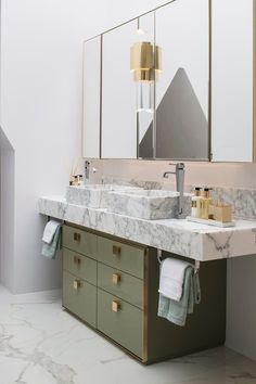 a bathroom with marble counter tops and green cabinets