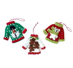 three christmas sweater ornaments hanging from strings