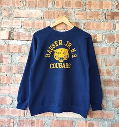 Vintage 80s Hauser JR. H.S. Cougars by Champion Sweatshirt Cougars Crewneck Cougars Pullover Embossed Logo Blue Color Women's Fit S Label : Champion Label Size : L (refer the measurement) Made in USA Materials from 92% Cotton 8% Polyester Used Item With Condition 7/10 Refer Picture. No Stain and No Holes. Lay Down Flat Measurement : - Width (armpit to armpit) and: 21 Inches - Length (shoulder to end of garment): 25 Inches We are selling used clothing with good condition. DO NOT EXPECT the item i Vintage Pre-shrunk Crew Neck Sweatshirt, Retro Blue Sweatshirt With Screen Print, Vintage Pre-shrunk Winter Sweatshirt, Vintage Crew Neck Sweater For College, Retro Blue College Sweatshirt, Retro Blue Sweatshirt For College, Blue Retro Sweatshirt For College, Vintage Crew Neck Tops For School, Vintage Blue T-shirt For Fall