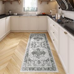 a kitchen with white cabinets and wooden floors, an area rug in the middle of the floor