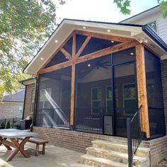 a covered patio with picnic table and stairs leading up to the front door, surrounded by trees