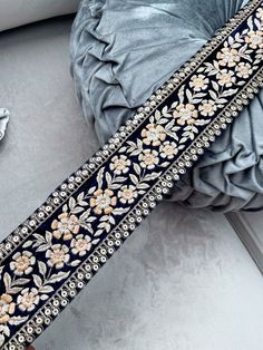 a black and gold beaded belt with flowers on the side next to a pillow