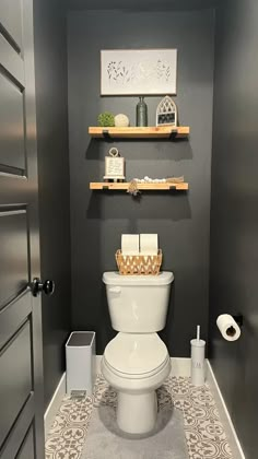 a white toilet sitting inside of a bathroom next to a wooden shelf filled with items