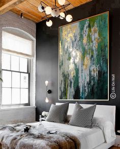 a large painting hanging above a bed in a room with black walls and wooden floors