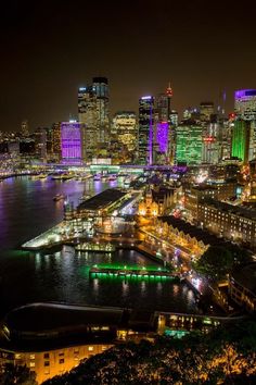 an aerial view of a city at night with lots of lights on the buildings and water