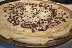 an uncooked pie with chocolate chips on it sitting on top of a stove