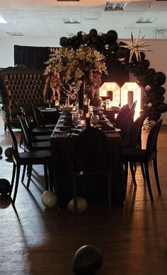 a dining room table set up with black chairs and balloons