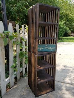 a wooden book shelf sitting next to a white picket fence