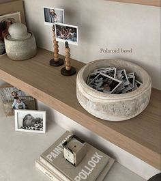 a wooden shelf topped with pictures and other items on top of a table next to a book