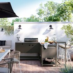 an outdoor kitchen with grill, table and chairs