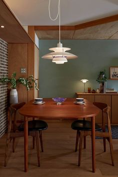 a dining room table with two chairs and a light fixture hanging from the ceiling