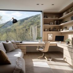 a living room filled with furniture and a large window overlooking a mountain side valley in the distance