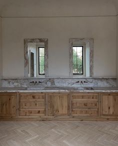 two sinks are in the middle of a room with wood flooring and marble counter tops