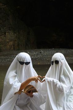 two people dressed in white floating on top of a body of water next to each other