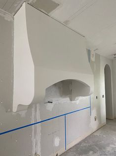 an unfinished room with a white stove and blue tape on the wall