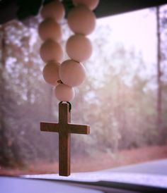 a wooden cross hanging from the side of a window