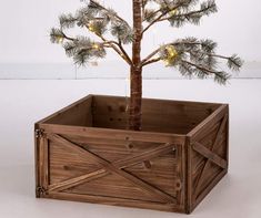 a small pine tree in a wooden box with lights on the top and bottom branches