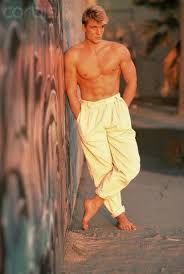 a shirtless man leaning against a wall