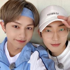 two young men are posing for a photo together, one is wearing a white hat and the other wears a blue jacket