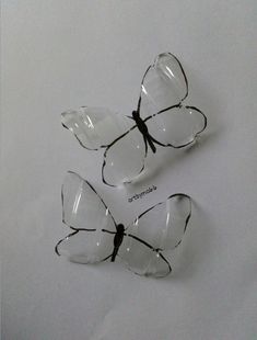 three clear butterfly shaped glasses sitting on top of a white tableclothed surface with black writing underneath them