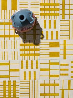 a blue vase sitting on top of a yellow and white wallpaper covered in squares