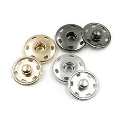 four different metal buttons on a white surface