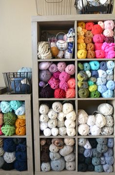 two shelves filled with yarn and crochet items next to a basket full of balls of yarn