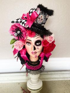 a woman's face is adorned with pink flowers and black feathers as she stands in front of a wall