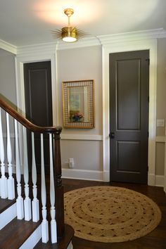 an entryway with stairs, rug and framed pictures on the wall above it in a home