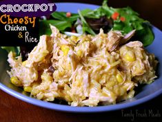 a blue plate topped with chicken and rice next to a green leafy salad on top of a wooden table