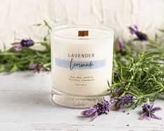 a lavender candle surrounded by flowers on a table