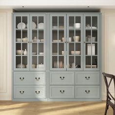 an empty chair sits in front of a blue china cabinet with glass doors and drawers