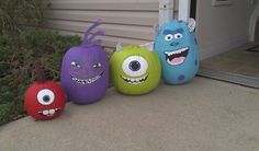 four halloween pumpkins with faces painted on them sitting in front of a home door