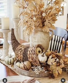 a table topped with a vase filled with lots of leaves and an owl figurine