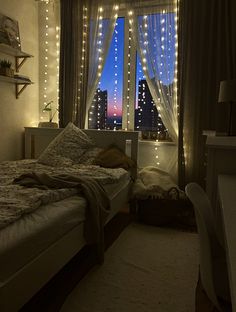 a bed room with a neatly made bed next to a large window covered in fairy lights