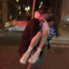 a man and woman kissing on the street at night